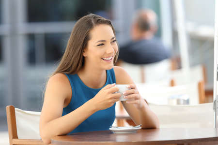 Confident woman smiling looking at side sitting in a coffee shop terraceの写真素材