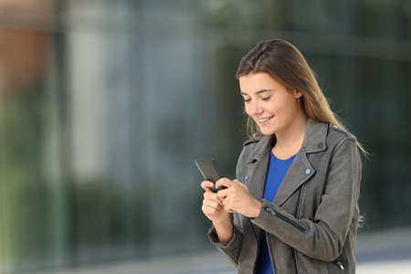 Single fashion teen using a smart phone walking on the streetの写真素材