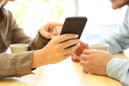 Close up of couple hands using a smart phone in a table of a coffee shop or homeの写真素材