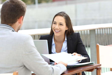 Two executives working sharing informs sitting in a bar terraceの写真素材