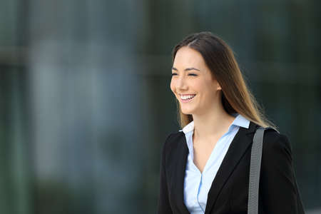 Happy confident executive walking on the street with an office building in the backgroundの写真素材