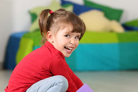 Little toddler girl smiling and looking at camera in her room at homeの写真素材