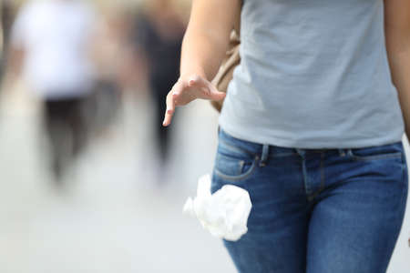 Close up of an irresponsible behavior of a woman throwing garbage to the floor while walking on the streetの写真素材