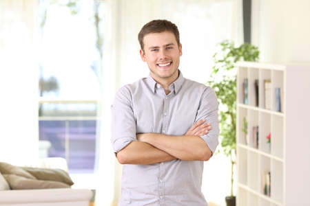 Happy homeowner portrait posing standing at home with furniture and window in the backgroundの写真素材