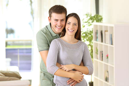 Portrait of a proud homeowners posing looking at you standing in the living room at homeの写真素材