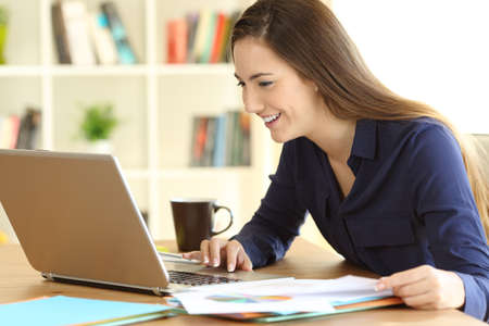 Happy freelancer working on line with a laptop on a desk at homeの写真素材
