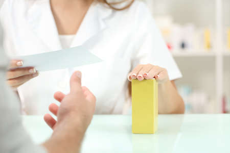 Close up of a pharmacist hands preparing medicine reading recipe in a pharmacy indoorの写真素材