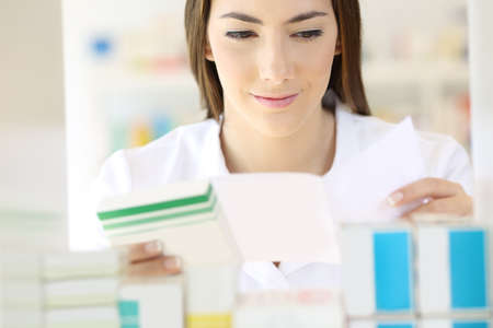 Front view portrait of a pharmacist reading prescription and preparing medicines in a pharmacyの写真素材