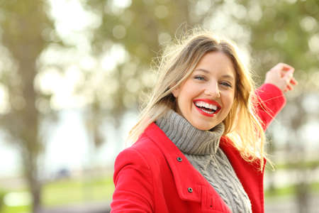 Portrait of a joyful beauty woman with perfect smile dancing carefree outdoors in a park in winter with copy space at sideの写真素材