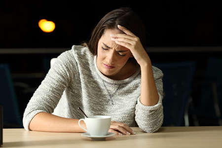 Front view portrait of a sad woman complaining in a restaurant