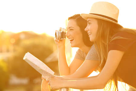 Two tourists photographing with a vintage camera from an hotel balcony at sunset