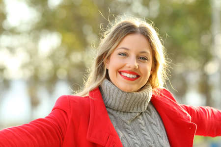 Front view portrait of a happy lady posing looking at camera in a park in winterの写真素材