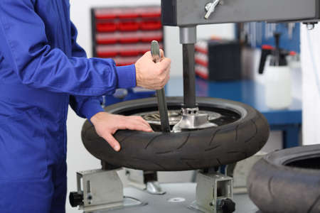Motorbike mechanic disassembling an old tire in a mechanical workshopの写真素材