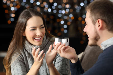 Happy boyfriend giving a gift to his girlfriend in the night at home