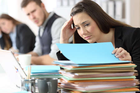 Worried employee looking at a lot of documents at office