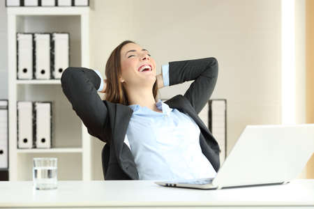 Portrait of a satisfied executive celebrating success with the arms on the head at officeの写真素材