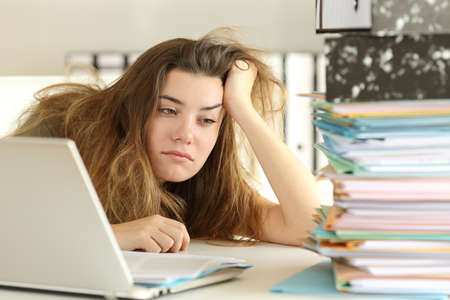 Tired and bored intern looking at amount of paperwork at office