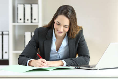 Front view portrait of an executive signing a document on a desktop at officeの写真素材