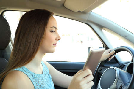 Side view portrait of a distracted driver reading phone message driving a car