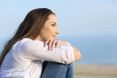 Side view portrait of a relaxed woman thinking and looking away on the beachの写真素材