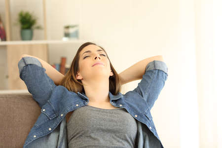 Woman relaxing sitting on a couch sitting on a couch in the living room at homeの写真素材