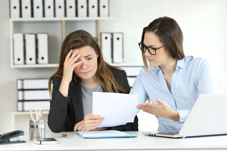 Boss scolding an intern showing a document at office