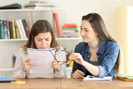 Student giving eyeglasses to her friend who is suffering eyesight problems
