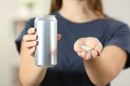 Front view close up of a woman hands holding a soda drink can and saccharin at homeの写真素材