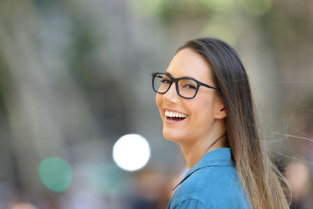 Pretty woman wearing eyeglasses smiling looking at camera in the streetの写真素材