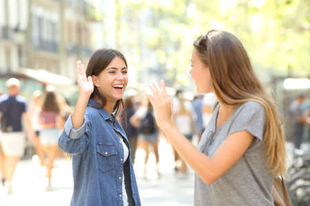 Two happy friends meeting and greeting in the streetの写真素材