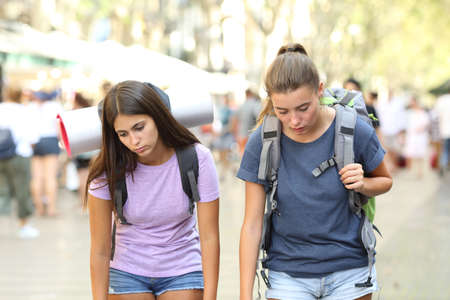 Front view of two tired backpackers traveling in a cityの写真素材