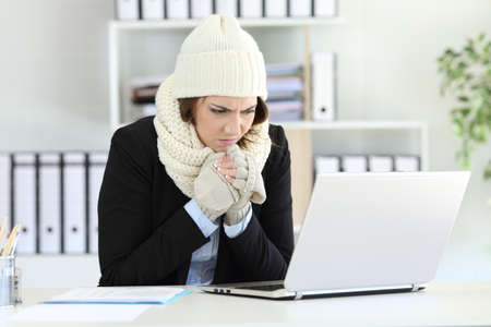 Cold angry executive working at office with a heater failure in winterの写真素材