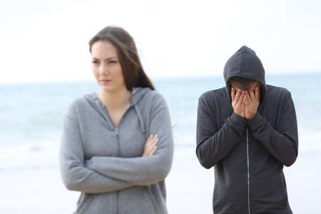 Couple break up on the beach with a girl leaving man aloneの写真素材