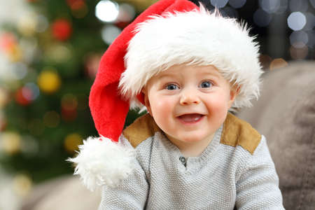 Cheerful baby looking at you in christmas on a couch in the living room at home