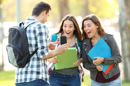 Student showing phone content to a friends outdoors in a park
