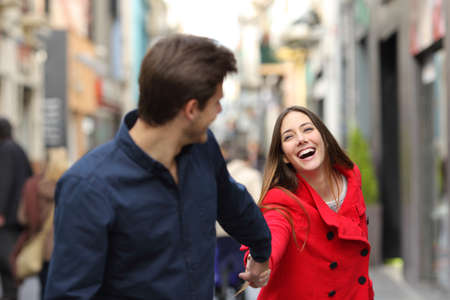 Happy couple running together in the street in winter