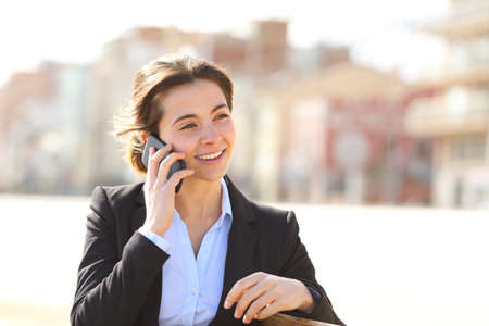 Happy businesswoman talking on phone sitting on a bench in a parkの写真素材