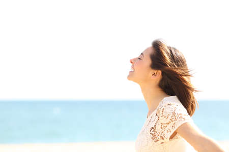 Side view portrait of a smiley lady breathing deep fresh air enjoying the wind on the beachの写真素材
