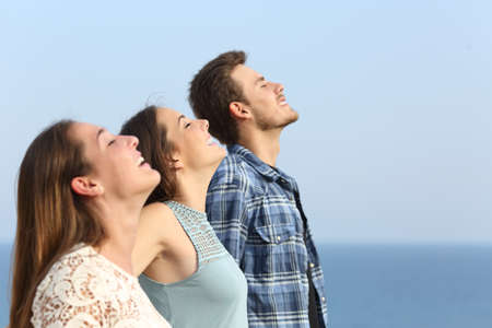 Profile of three happy friends breathing deep fresh air on the beachの写真素材