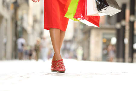Front view close up portrait of a beauty woman legs walking holding shopping bagsの写真素材