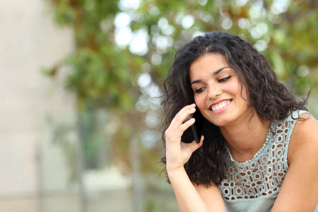 Happy lady talking on smart phone sitting in a parkの写真素材
