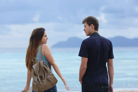 Back view of two frustrated tourists looking each other a cloudy day on vacationの写真素材