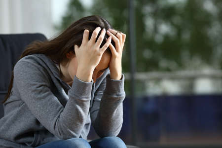 Sad woman complaining alone sitting on a couch at home