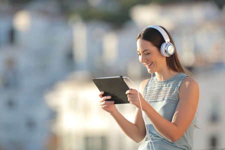 Happy woman watching media content in a tablet in a townの写真素材
