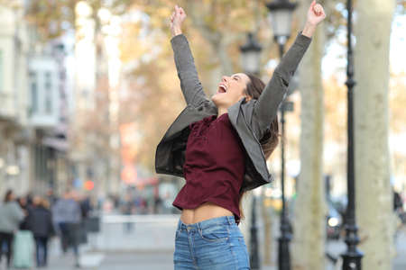 Excited woman jumping celebrating successs in the street