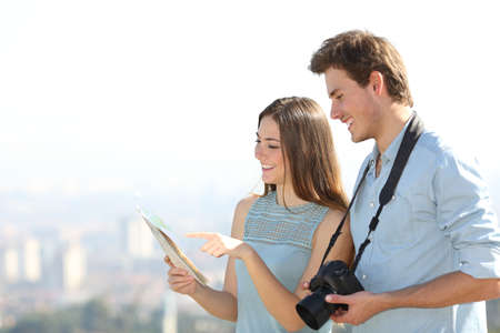 Happy tourists checking paper guide on holiday in a city outskirtsの写真素材