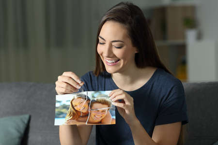Woman rebuilding couple photo after reconciliation sitting on a couch in the living room at homeの写真素材