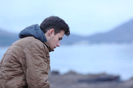 Side view ortrait of a sad man in winter on the beach complainingの写真素材