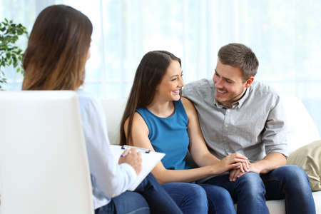 Happy marriage after couple therapy sitting on a couch at home or consultationの写真素材