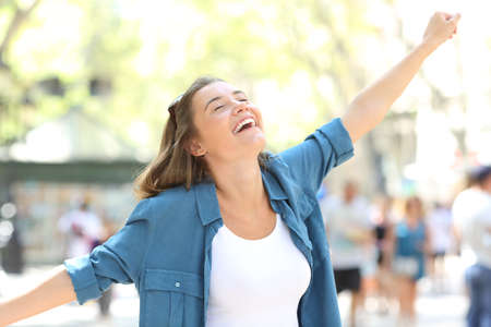 Excited girl celebrating success stretching arms in the streetの写真素材